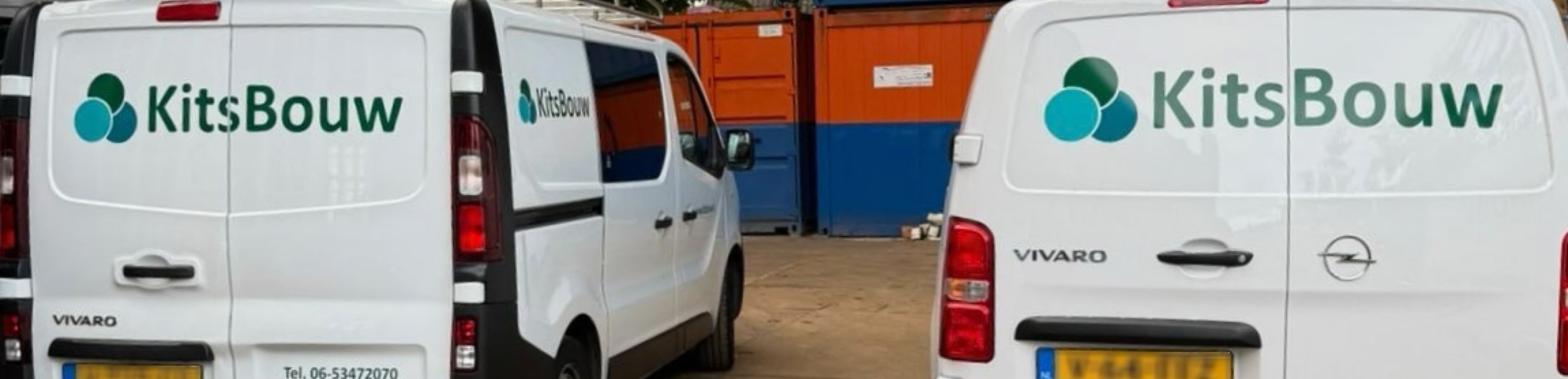 Twee witte werk bussen met het logo "KitsBouw" geparkeerd voor gekleurde containers op een bouwplaats.